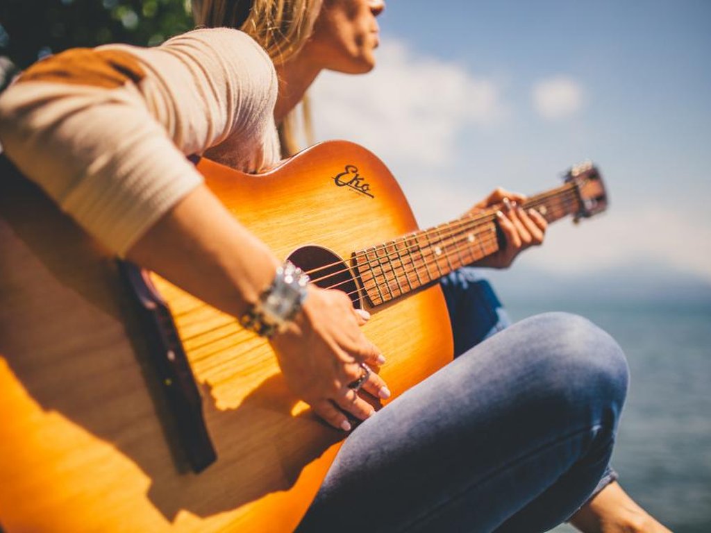 A musician alone with an acoustic guitar, trying out an idea.