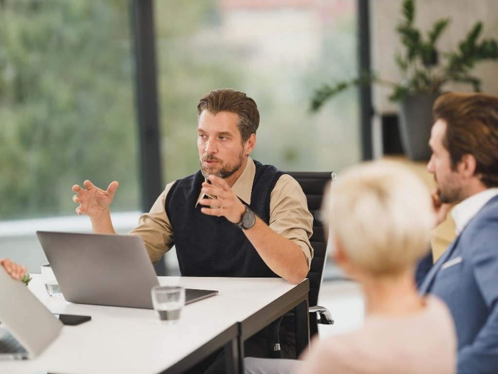 A man making a point in a meeting while his colleagues listen.