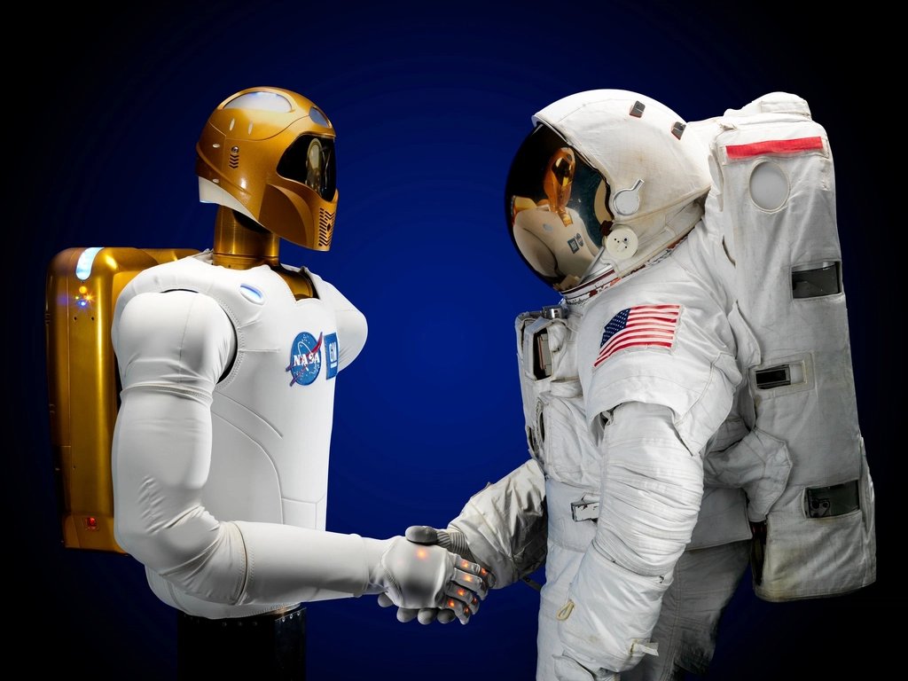 A humanoid robot shaking hands with an astronaut.